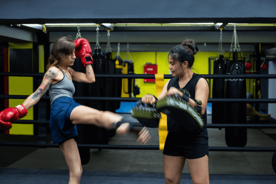 Lutadora em treino de manopla usando luvas e calcanheira, ilustrando o guia completo sobre qual a melhor marca de kit de Muay Thai.